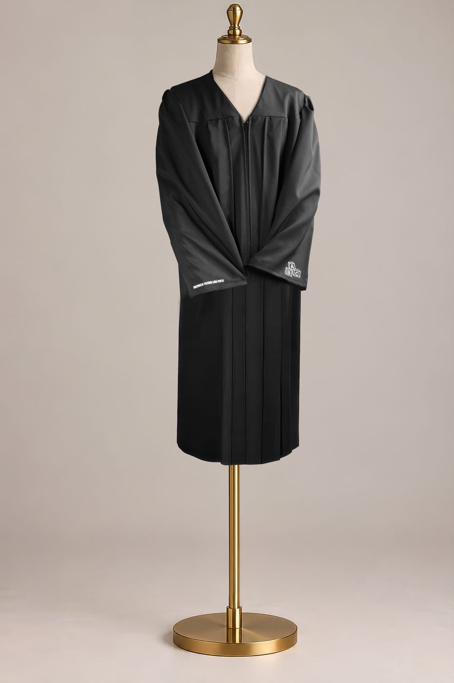 Toga negra cerrada sobre un maniquí, con un nombre bordado en la manga.